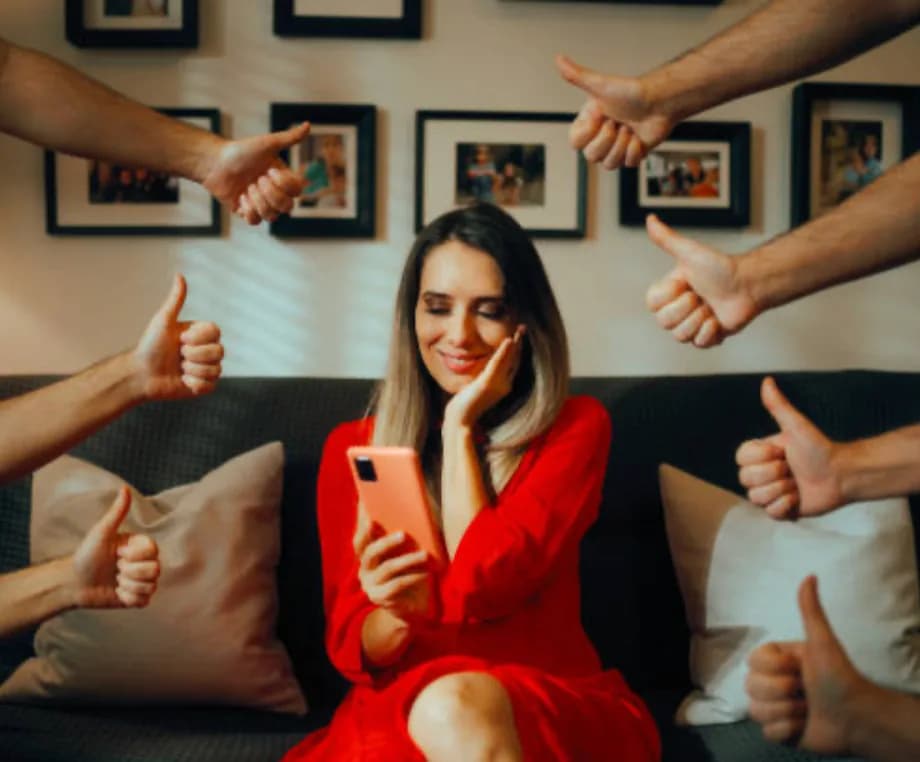 Pessoa recebendo sinais de aprovação enquanto olha para o celular.